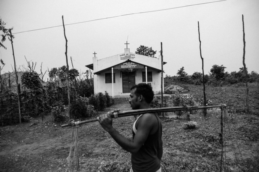 A Muria man, fetching water, walks past a church in Ramachandrapuram, an early Muria settlement in the region.