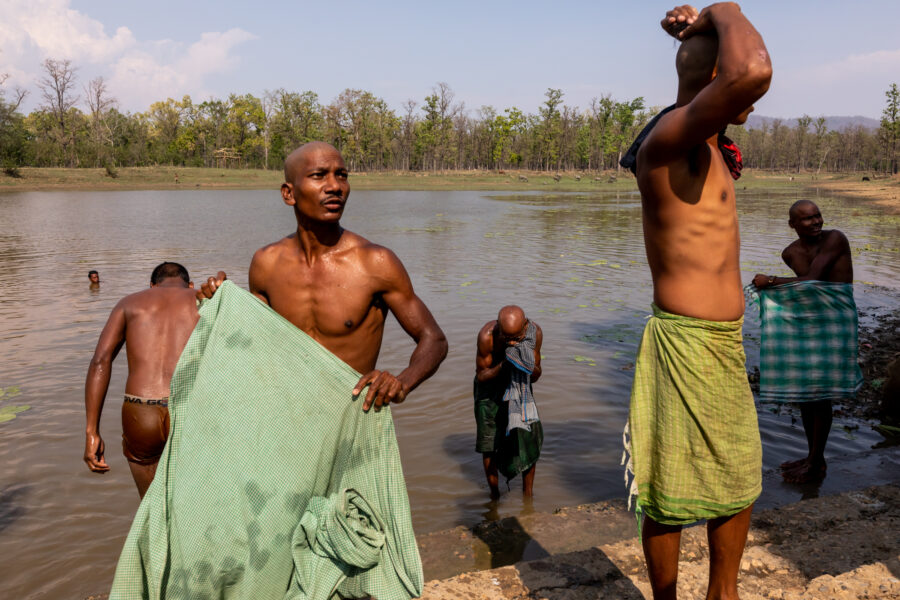 Suspecting she was there to vaccinate them, a member of a Baiga adivasi family taking a ritual bath, warns a JSS health worker (not seen in the photo) in Jamunahi in Mungeli, Chhattisgarh. May 13, 2021.