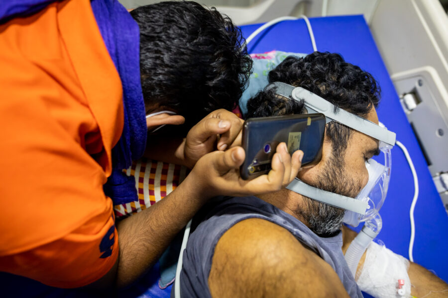 Ashik Parvez, 28, plays an Islamic prayer on his mobile phone for his father Nabi Khan, 50, who was critically ill in the COVID-19 ICU at the Government Medical College Hospital in Ambikapur in Surguja, Chhattisgarh.  The ICU is being run by Sangwari, a group of doctors committed to rural healthcare, in collaboration with the hospital. May 23, 2021.