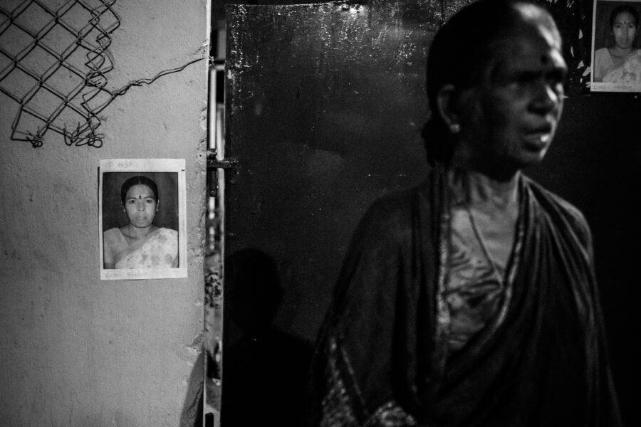 A junior artiste waiting early in the morning for casting agents to arrive and choose actors, stands in front of obituaries for a junior artiste who had passed away a few days ago. August 2015.