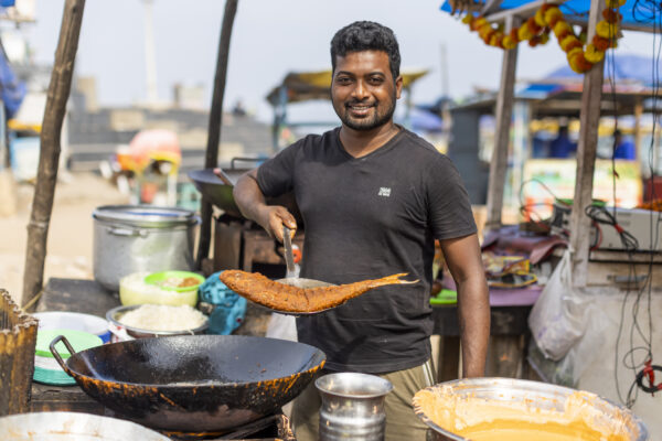 18 November 2022, Visakhapatnam, Andhra Pradesh, India- Shyam Prasad Gopisetty,29, poses for a portrait at his fried fish stall on Ramakrishna Beach. The place is popular with locals and tourists for its fresh seafood.  This photo mission has been supported by Central Institute of Fisheries Technology (ICAR- CIFT), India.