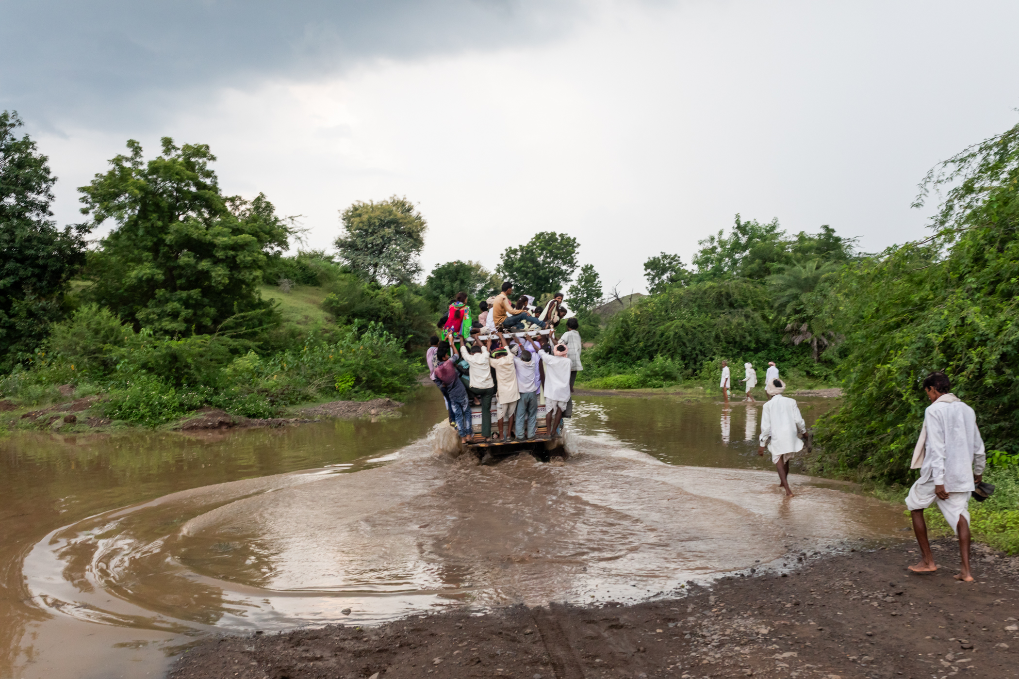 Waters Close Over Us | | Harsha Vadlamani A pickup truck carrying Adivasis (Indigenous people) up the hill towards Chandankhedi in Dhar, Madhya Pradesh, passes through the rushing backwaters of the Sardar Sarovar Dam's reservoir. On June 17, all gates of the controversial dam on the river Narmada were closed together for the first time, leading to the gradual submergence of areas upstream.