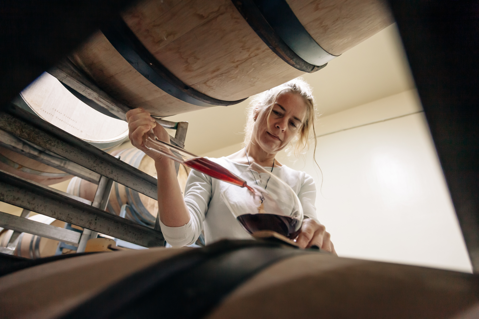 Close-up of a winemaker drawing wine from a barrel to check quality and taste, photographed to highlight detail and brand storytelling.